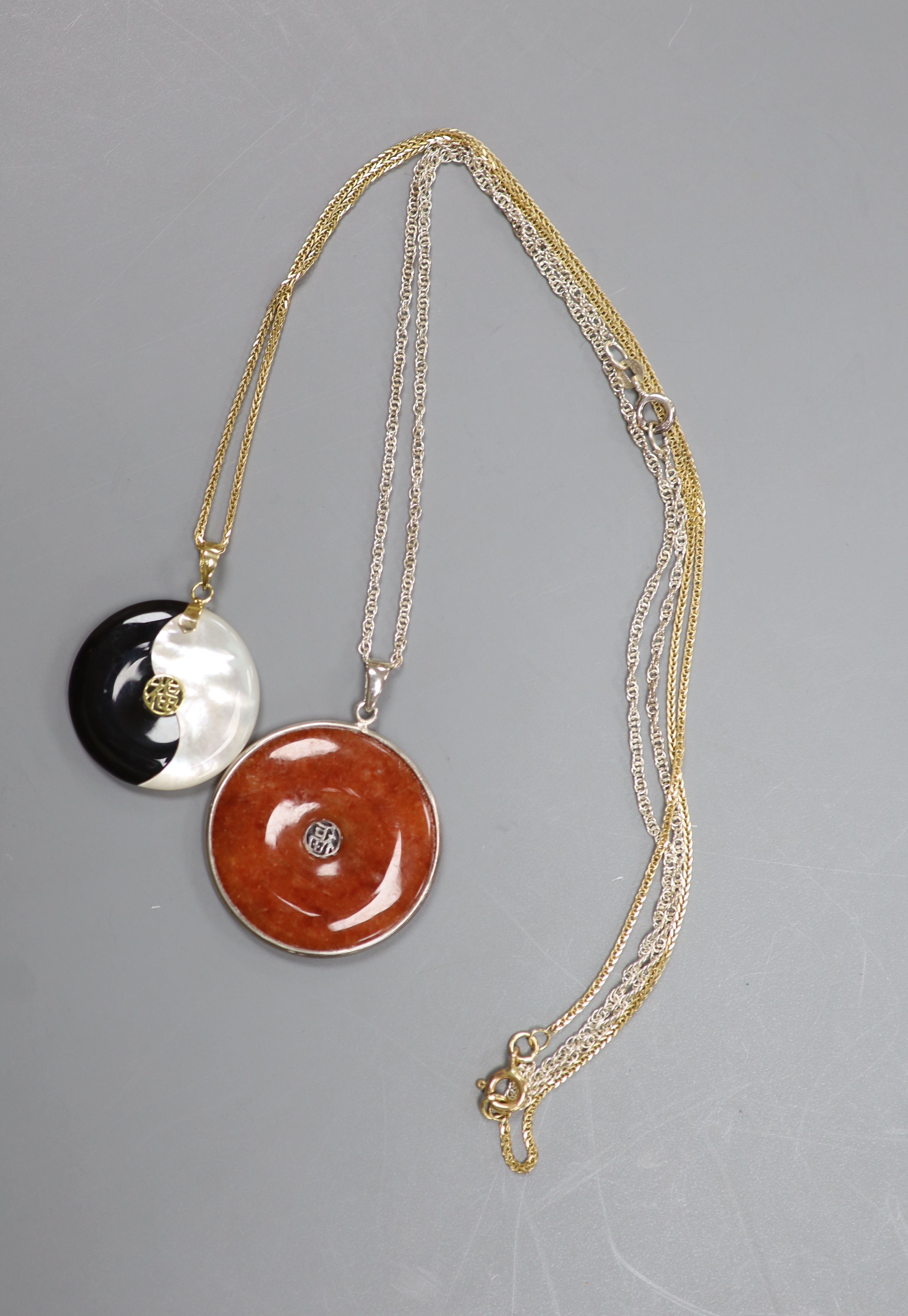 A Chinese gold-mounted black and mother of pearl Yin Yang pendant on 9ct gold chain and a silver-mounted agate disc pendant